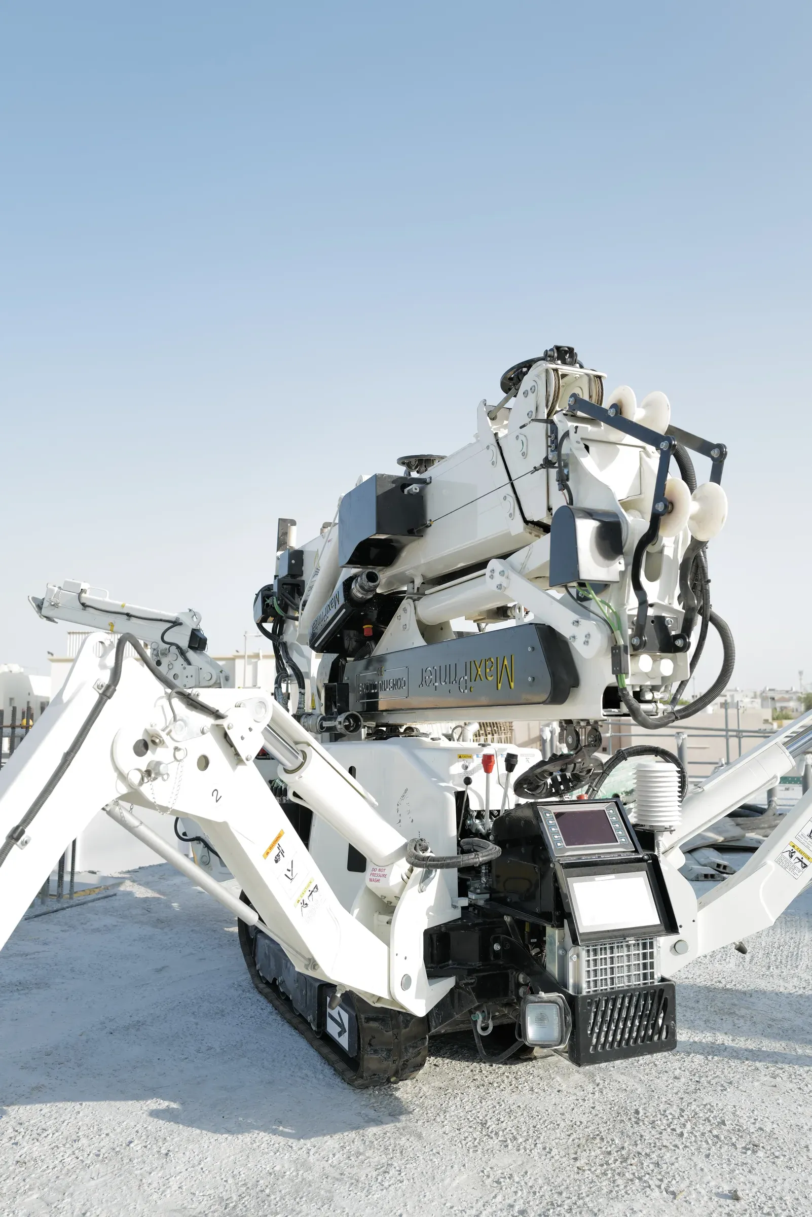 MaxiPrinter from behind, legs deployed, against a pale sky